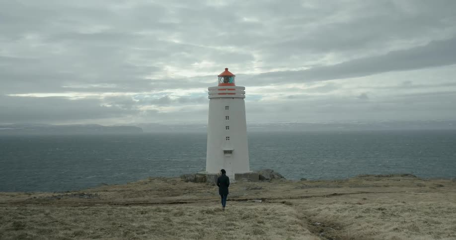 Person walking towards a lighthouse