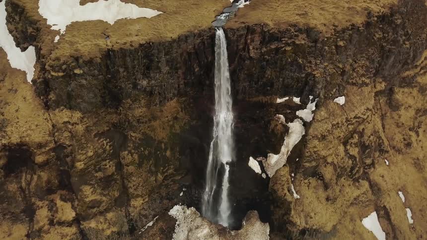 Water falls off the side of a stone mountain