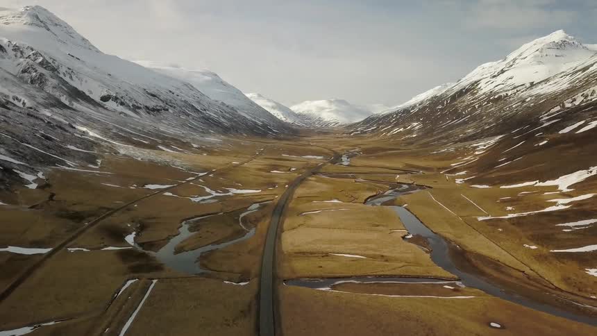Looking out over a vast valley surrounded by snow covered mountains