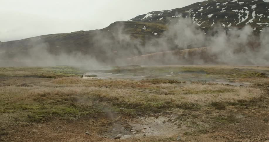 Steam lifts up from the ground in front of a mountain