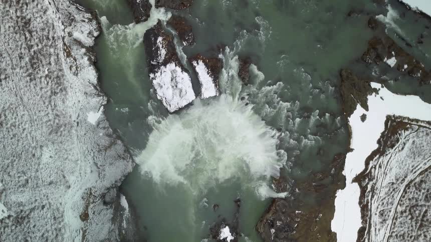 Water flows down a stream and pools together between the icy cliffs