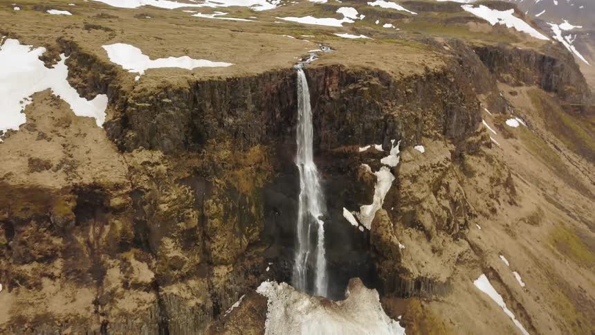 A waterfall flows over a cliff
