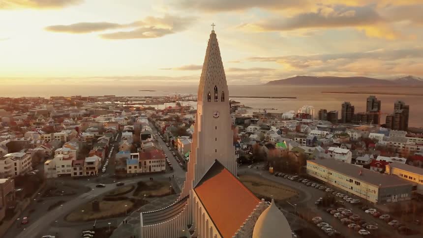 Spire rising into the sky from a building in a town near the sea on a cloudy day