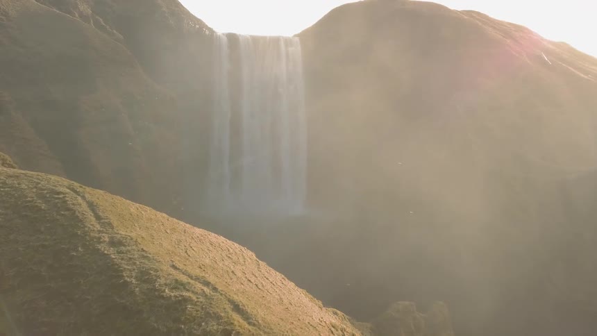 Birds fly near a waterfall on a sunny day