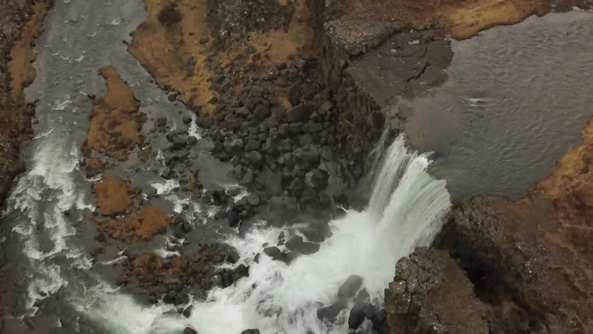 A waterfall flows over a rocky cliff
