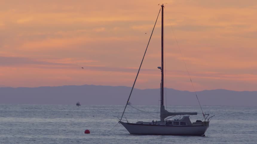 Boat is anchored out in the water at sunset