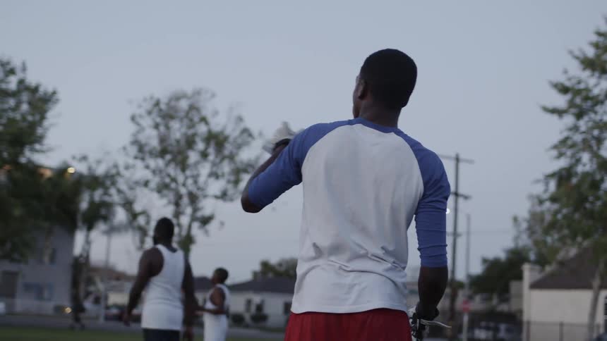 Teenage boys are playing football in a park at dusk