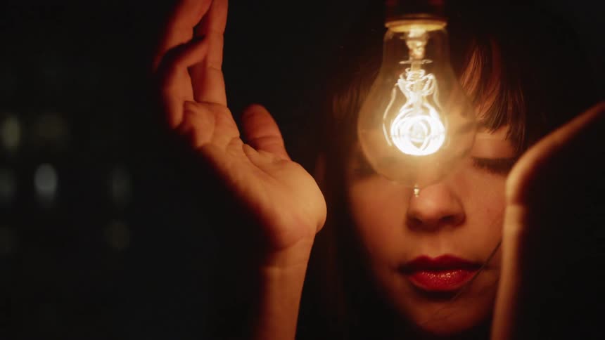 A woman looks at a glowing light bulb