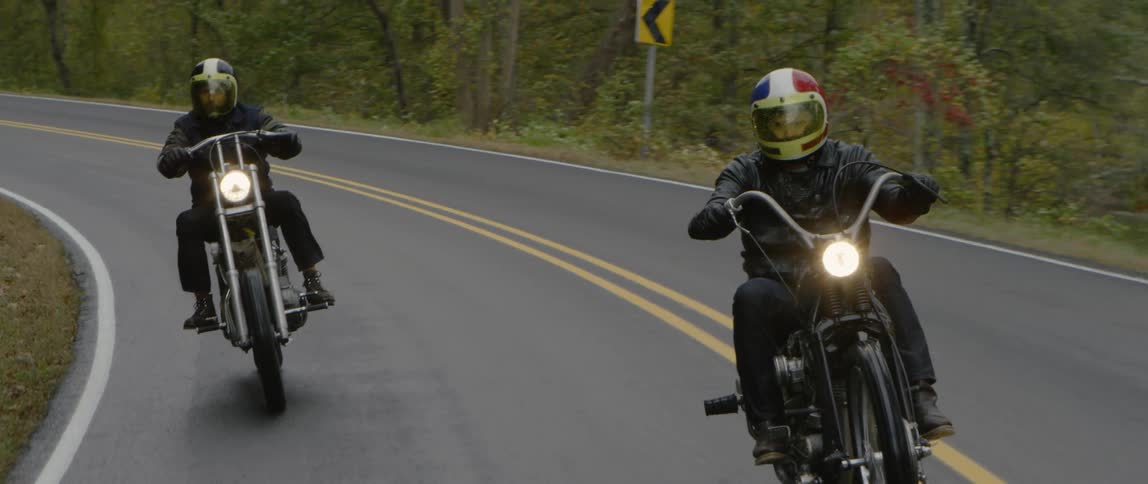 People travel by motorcycle on a winding country road