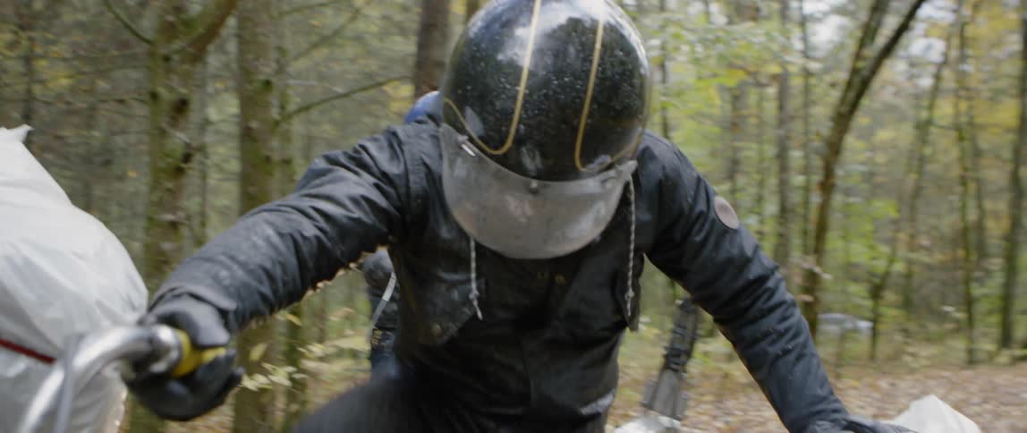 A man starts a motorcycle in a forest