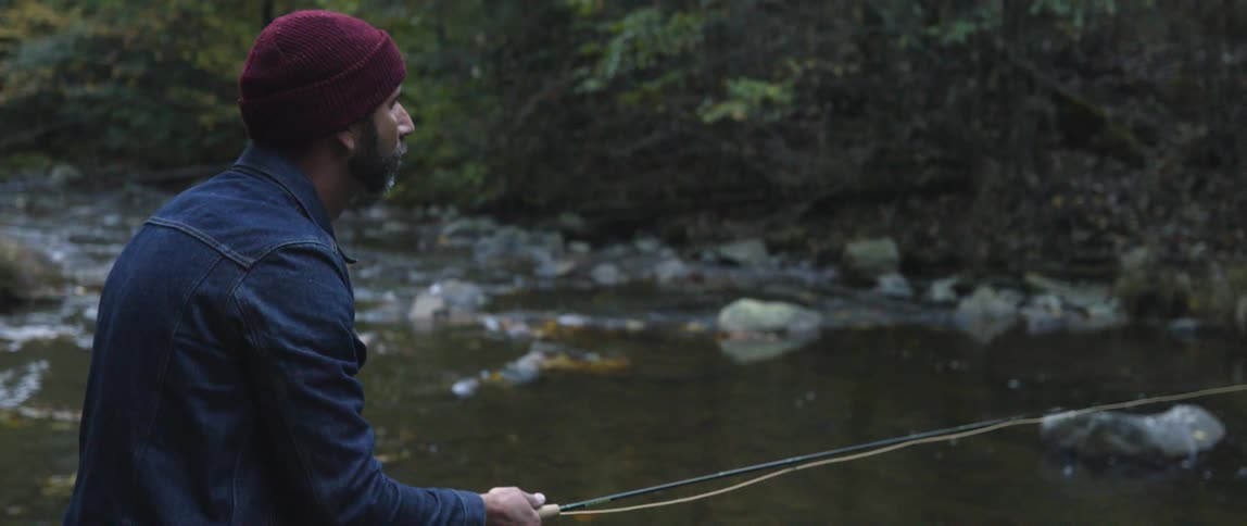 A man fly fishes in a stream