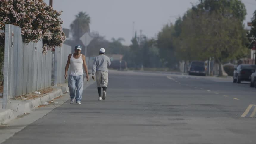 Two men are walking in opposite directions through a parking lot during the day