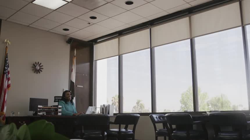A woman sits at a desk in a large office