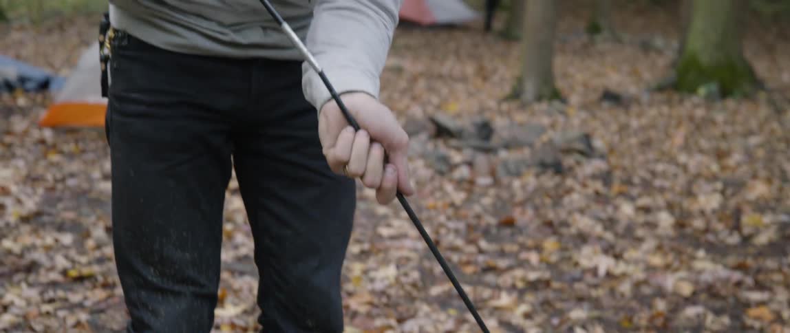 A man sets up a tent in a forest