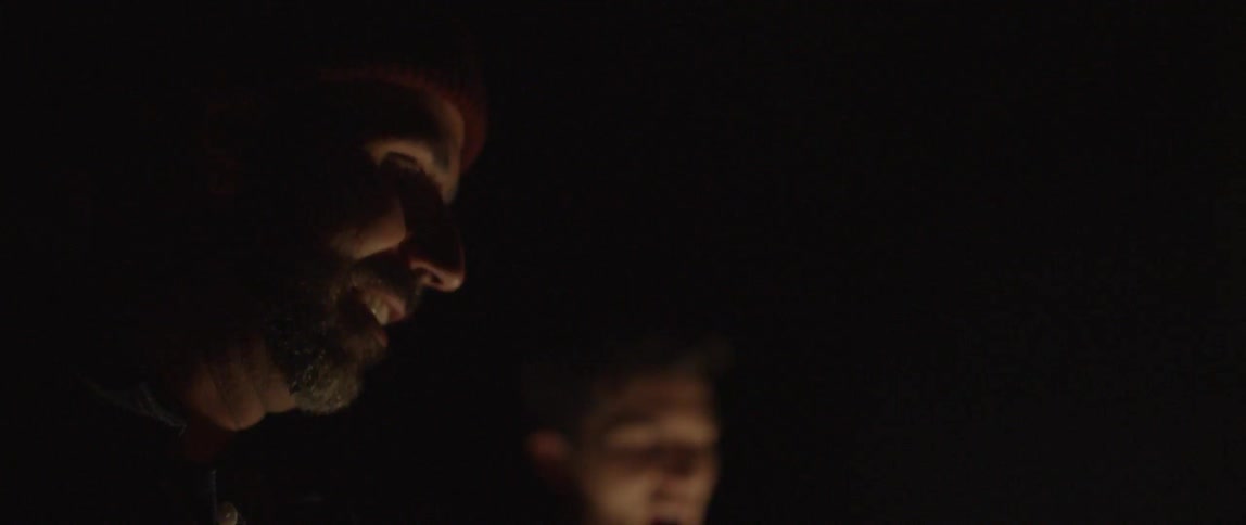 Men are gathered around a campfire at night