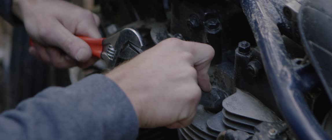 A man makes repairs with a wrench