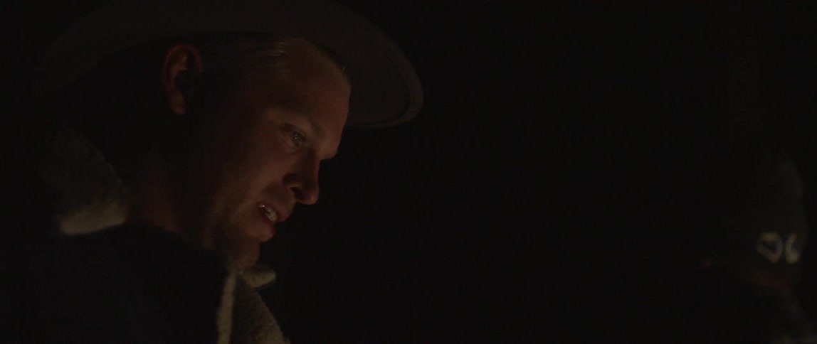 A man is standing outside in the light of a campfire