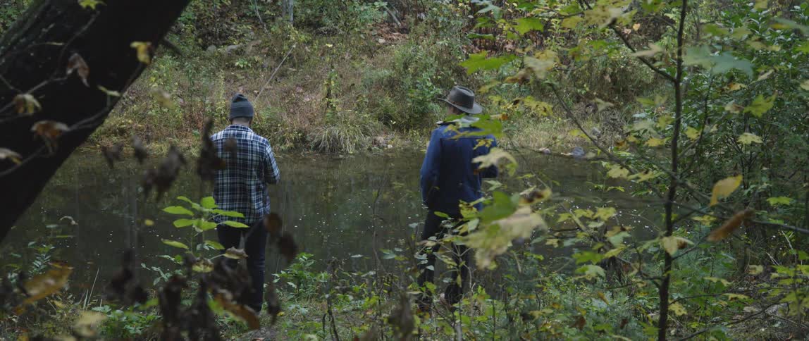 Two men fish in a stream