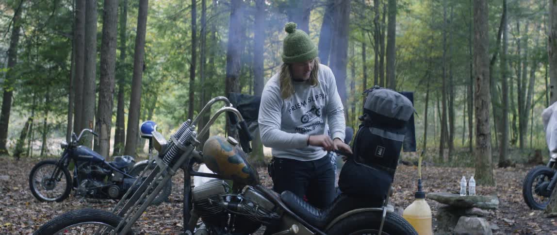 Motorcyclists setting up camp in the forest and cooking