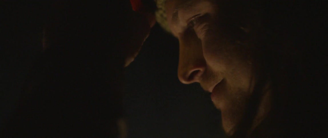 A man wearing a headlamp is outside talking at night
