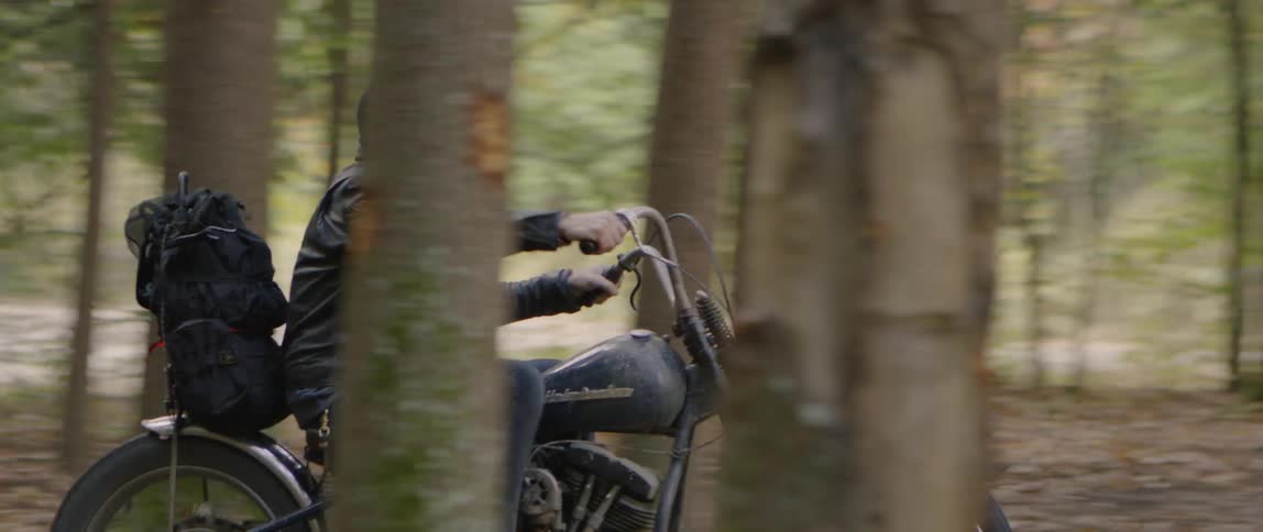 A man rides a motorcycle in a forest