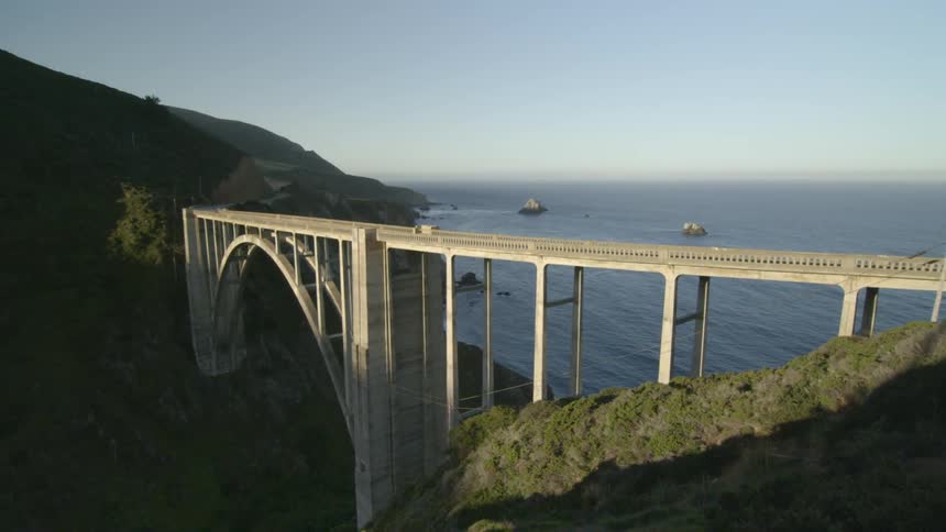 A bridge gaps two cliffs with boats in the water below