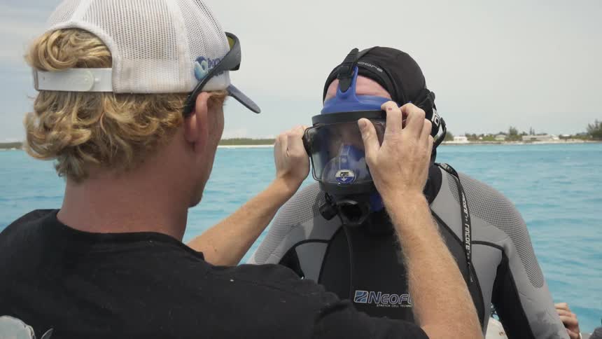 A man adjusts a scuba divers mask for him