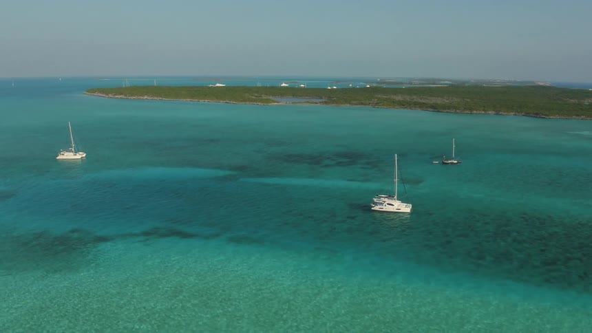 Boats sit on the surface of clear blue ocean water