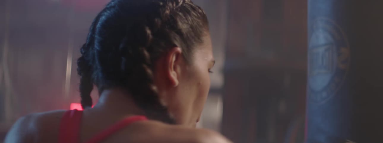 Woman wearing boxing gloves strikes a punching bag