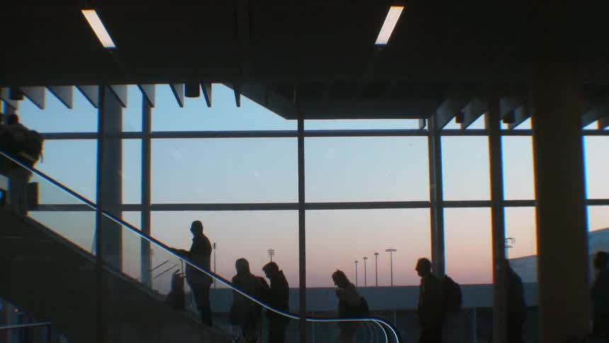 People going up on an escalator in front of a large window
