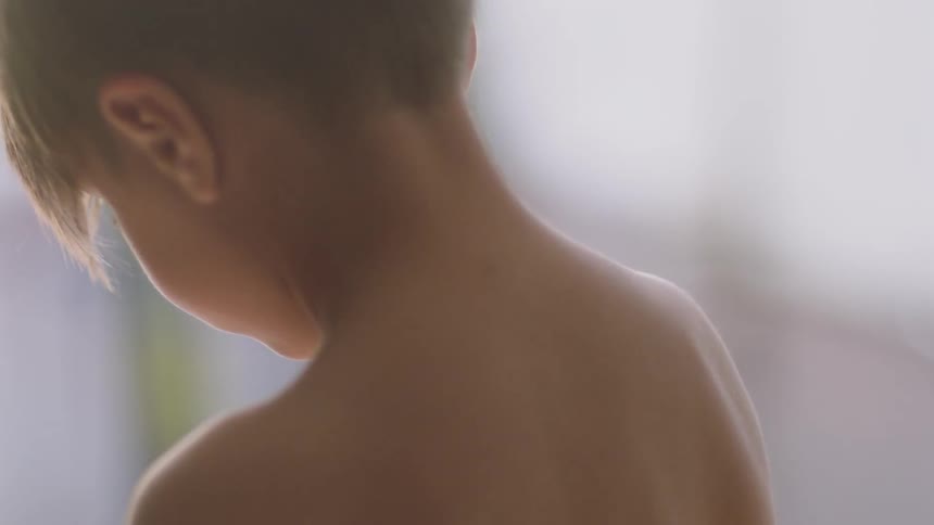 Shirtless child looks down on a sunny day