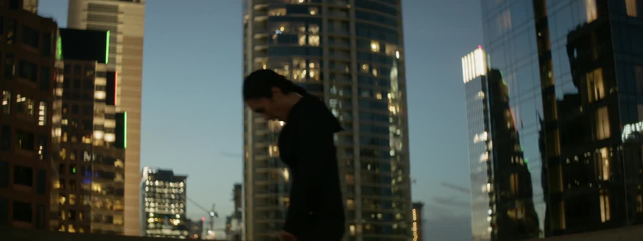 Woman hopping around on a rooftop in a large city
