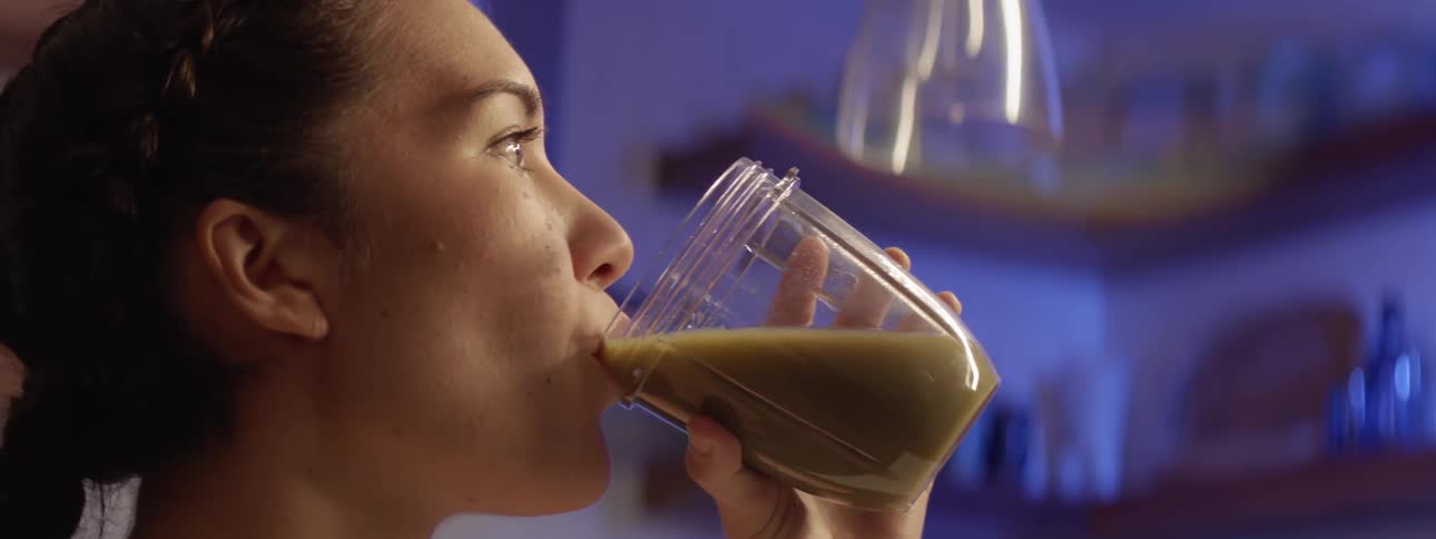 A woman drinks a green smoothie