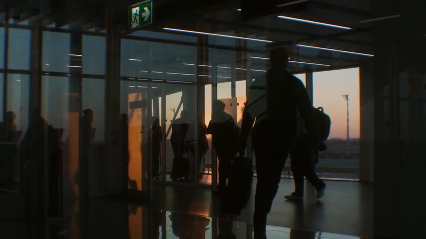 Travelers walk in an airport at sunset