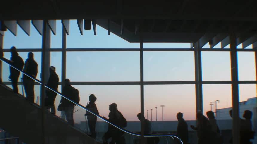 Travelers ride up an escalator in an airport