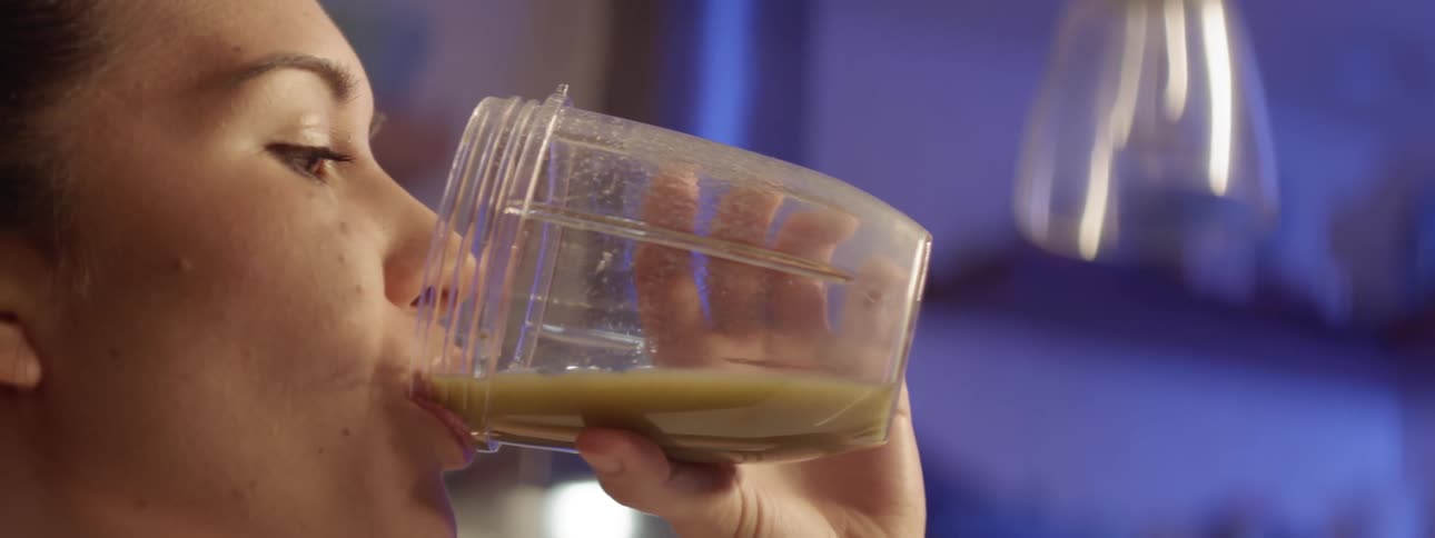 A woman drinks a smoothie at home