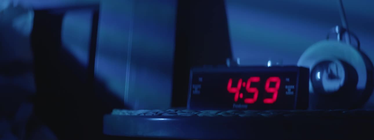 An alarm clock is hit by a person as it registers 5:00