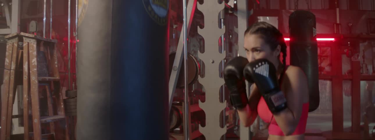 Woman boxer working out with a heavy bag in a gym