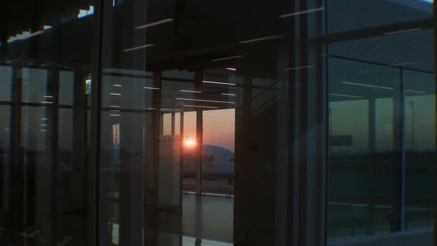 Sun setting behind a plane at an airport