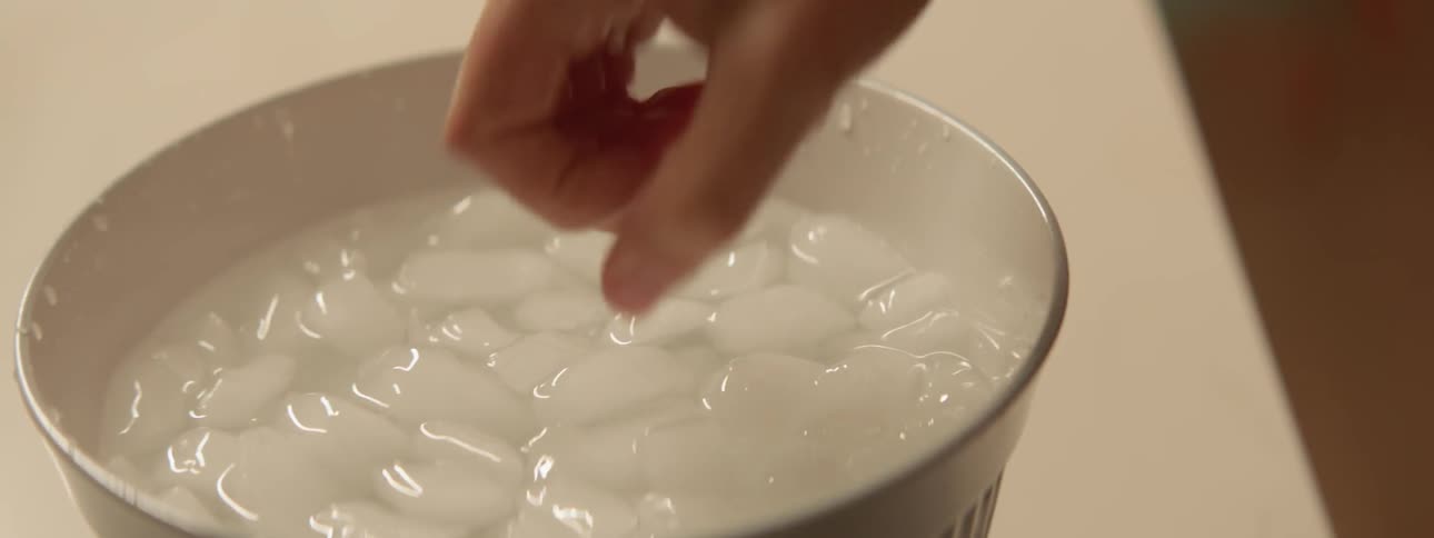 A woman puts her hand in a bowl of ice water