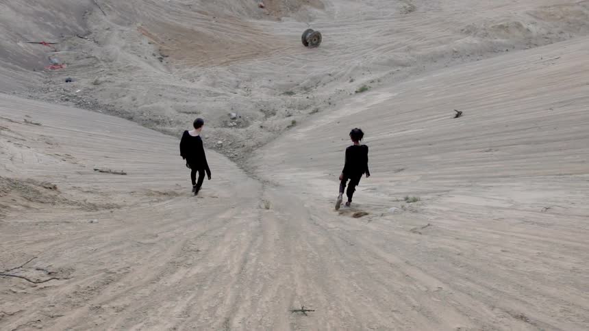 People walking down a steep dirt hill