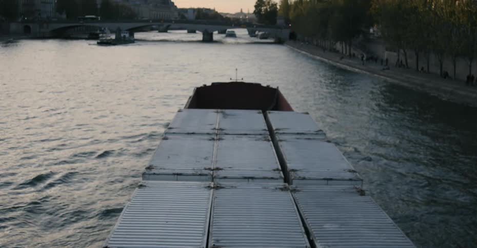 A barge carrying shipping containers travels down the canal