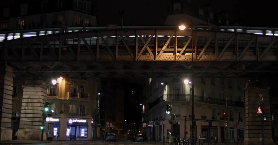A train drives over a city bridge at night