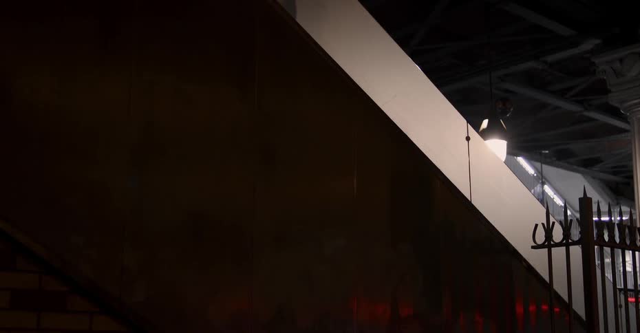 A shadow of a person riding an escalator travels up the wall