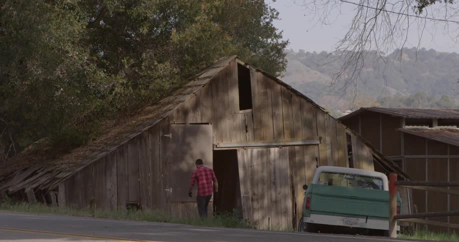 Man walking out of a barn loading large pieces of wood in his truck