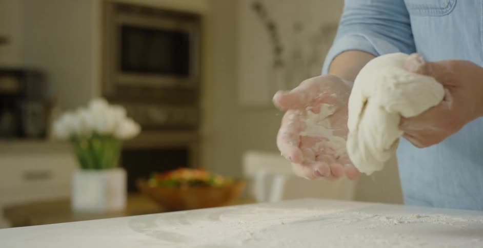 A woman kneads dough in a home kitchen