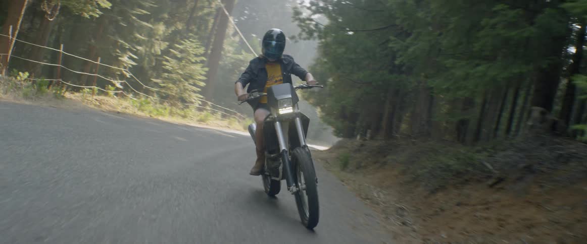 A woman rides a motorcycle in a zigzag pattern