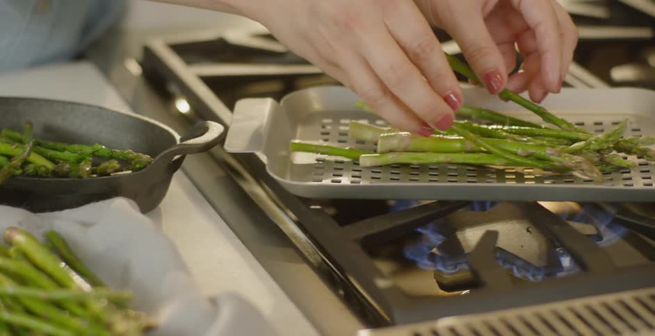A woman cooks asparagus on the stove top