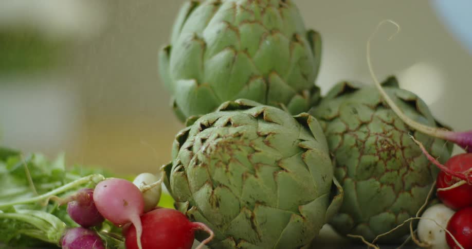 A bunch of artichokes next to a bunch of radishes