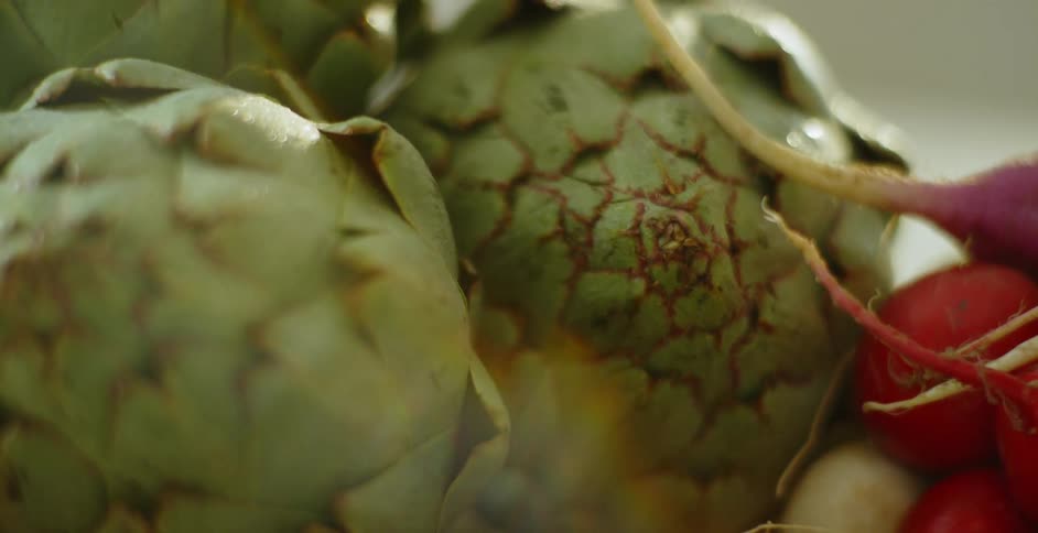 Artichokes and radishes sit in a pile